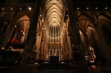 The soaring Gothic nave of Cologne Cathedral after dark, looking east to the choir.