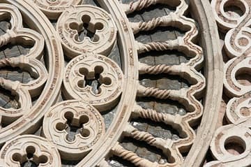 Detail of rose window in the upper church facade. Completed in 1280, it is Romanesque in style, showing similarities to Spoleto Cathedral and other churches in the region. The elegant rose window, flanked by the symbols of the Four Evangelists, still contains traces of golden mosaic. Sculptures of mythical creatures decorate the horizontal moldings of the facade.